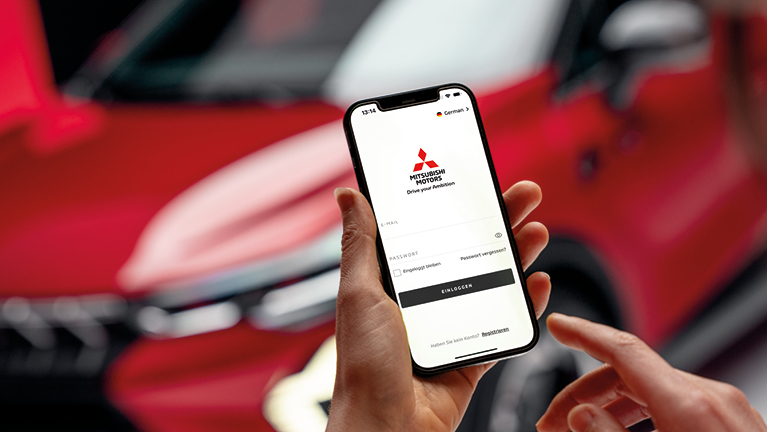 Hand hält Smartphone mit geöffneter Mitsubishi Motors App vor rotem Mitsubishi ASX im Hintergrund
